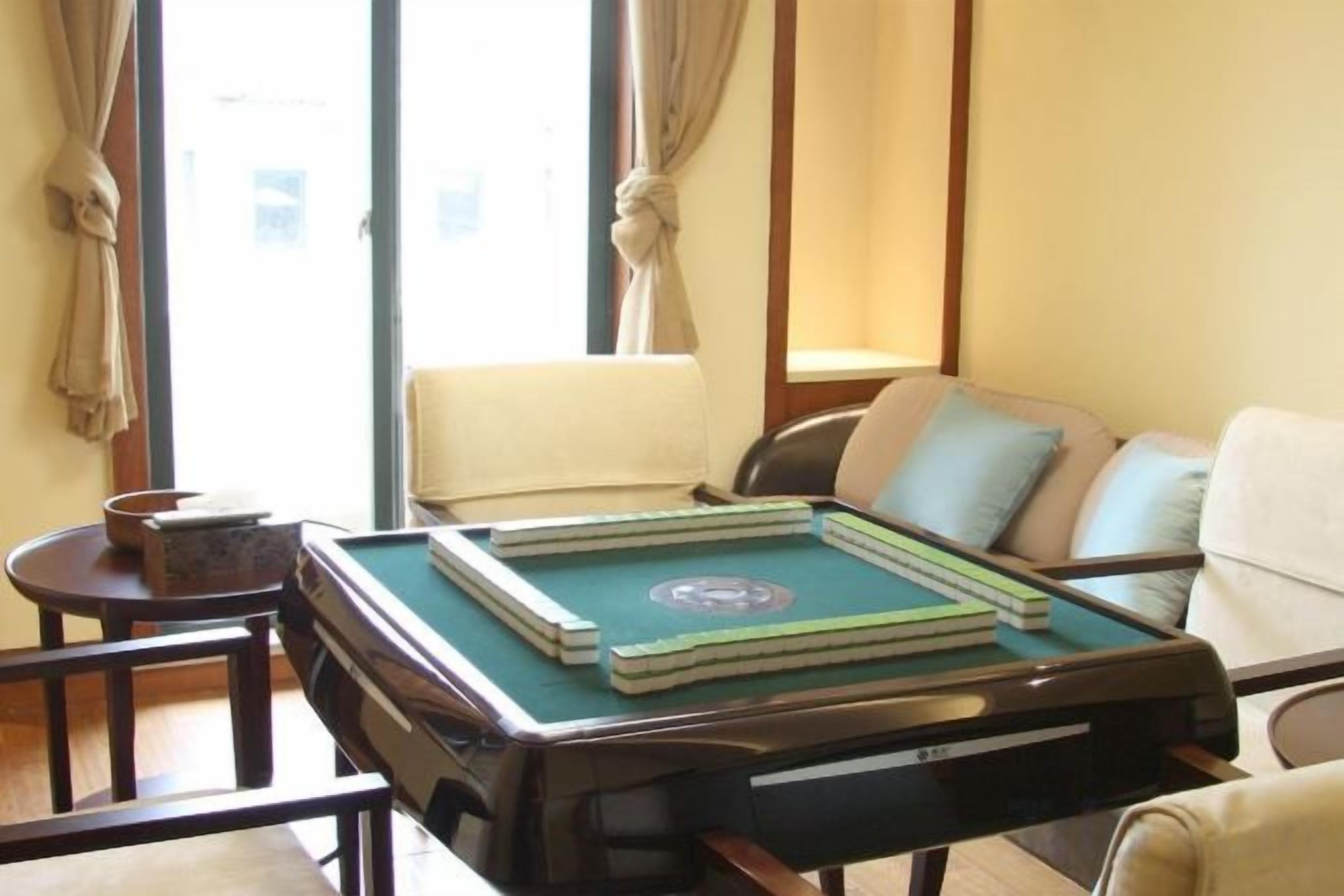 A room with a pool table, a sofa, and a window with curtains.