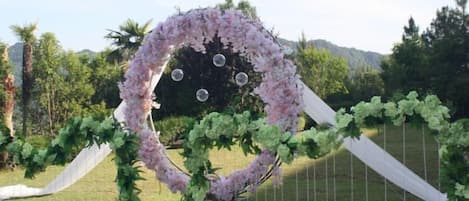 Un arco nupcial al aire libre decorado con flores y un fondo blanco drapeado.