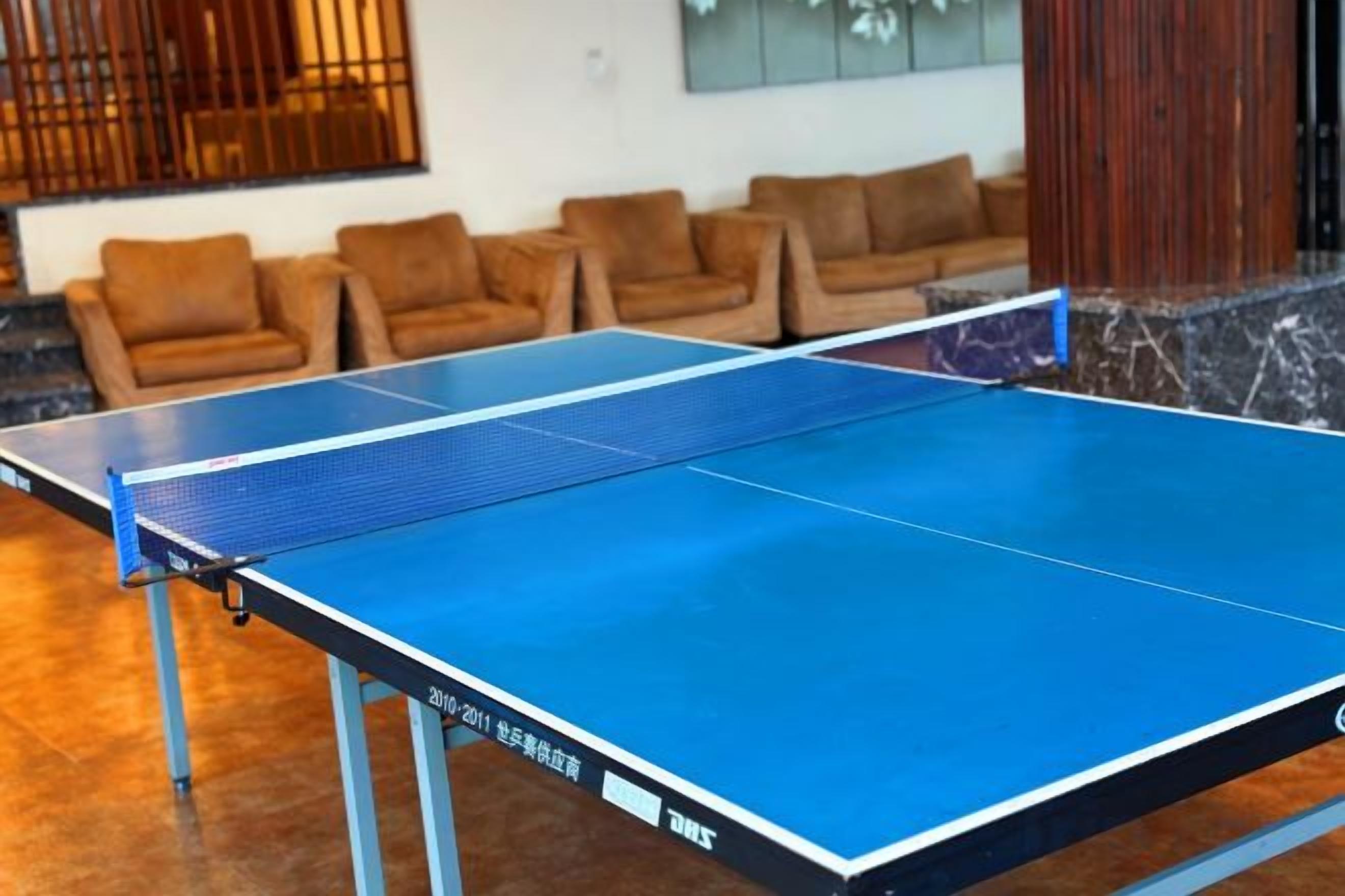 A ping pong table in a room with a seating area.