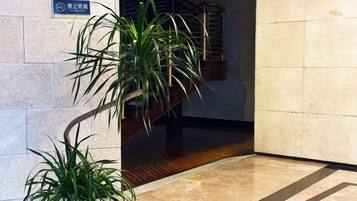A corner with a potted plant, a sign, and a staircase.