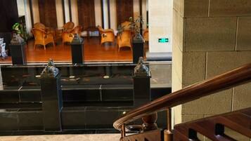 A lobby with a reception desk, wooden chairs, and a staircase.