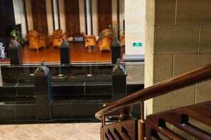 A lobby with a reception desk, wooden chairs, and a staircase.