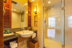 A modern bathroom with a large mirror, a sink, and a glass-enclosed shower.