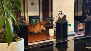 A lobby with a polished floor, wicker chairs, potted plants, and a statue. - Jade Jianguo Resort Zhejiang Pan'an (Pan'an)