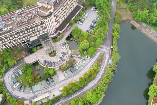 Vista aérea de un edificio moderno con un estacionamiento, una carretera curva y un río.