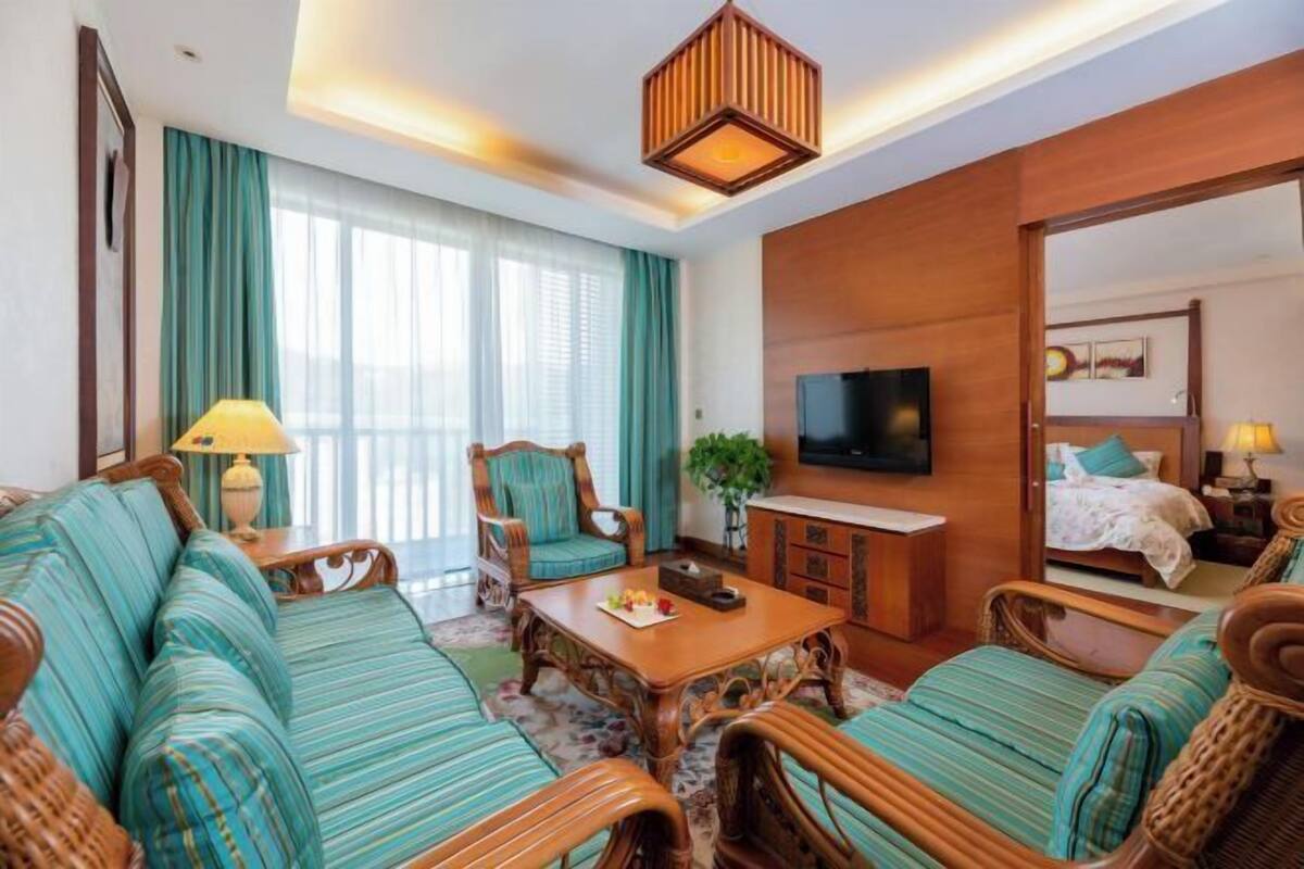 Quarto de hotel com sofá, mesa de jantar, televisão e cama.