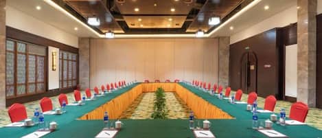 A conference room with a long table, red chairs, and a carpeted floor.