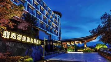 A hotel entrance with a modern design, a large sign, and a well-lit pathway leading to the building.