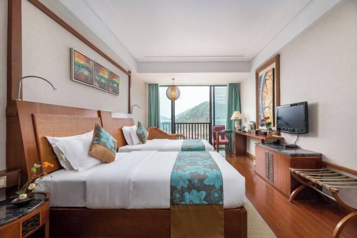 Quarto de hotel com duas camas, televisão, varanda e obras de arte nas paredes.