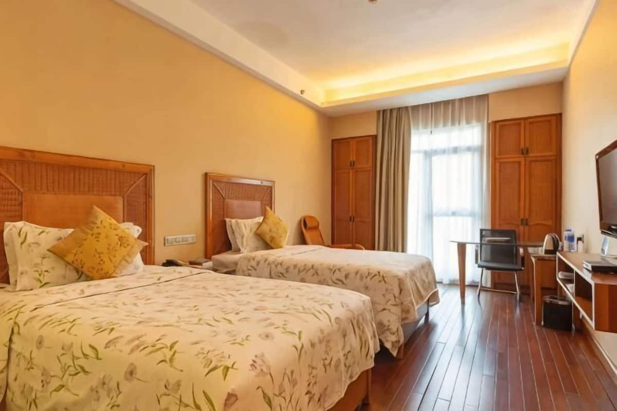 A hotel room with two beds, a desk, a television, and a wardrobe.