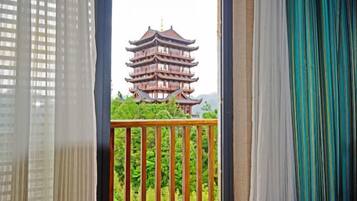 Une pagode traditionnelle à plusieurs niveaux, vue à travers un balcon orné d’une balustrade en bois.