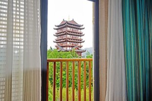 Una pagoda tradicional de varios niveles visible a través de un balcón con barandilla de madera.