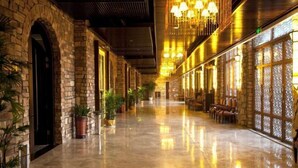 A spacious corridor with stone walls, potted plants, and seating areas. - Jade Jianguo Resort Zhejiang Pan'an (Pan'an)