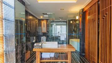 A modern bathroom with a marble floor, a wooden vanity, and a glass shower enclosure.