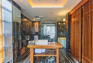 A modern bathroom with a marble floor, a wooden vanity, and a glass shower enclosure.