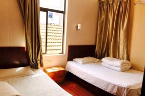 A room with two beds, a nightstand, a window with curtains, and a wall-mounted light. - Xinjie Hostel (Shanghai)