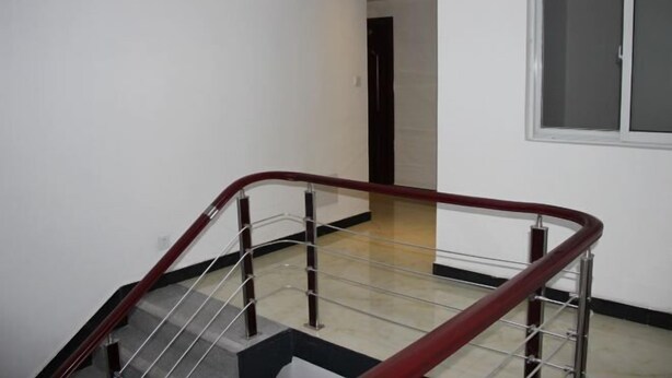A staircase with a red handrail and metal balusters, leading to a room with a white wall and a window. - Xiangli Renjia Inn (Huangshan City)