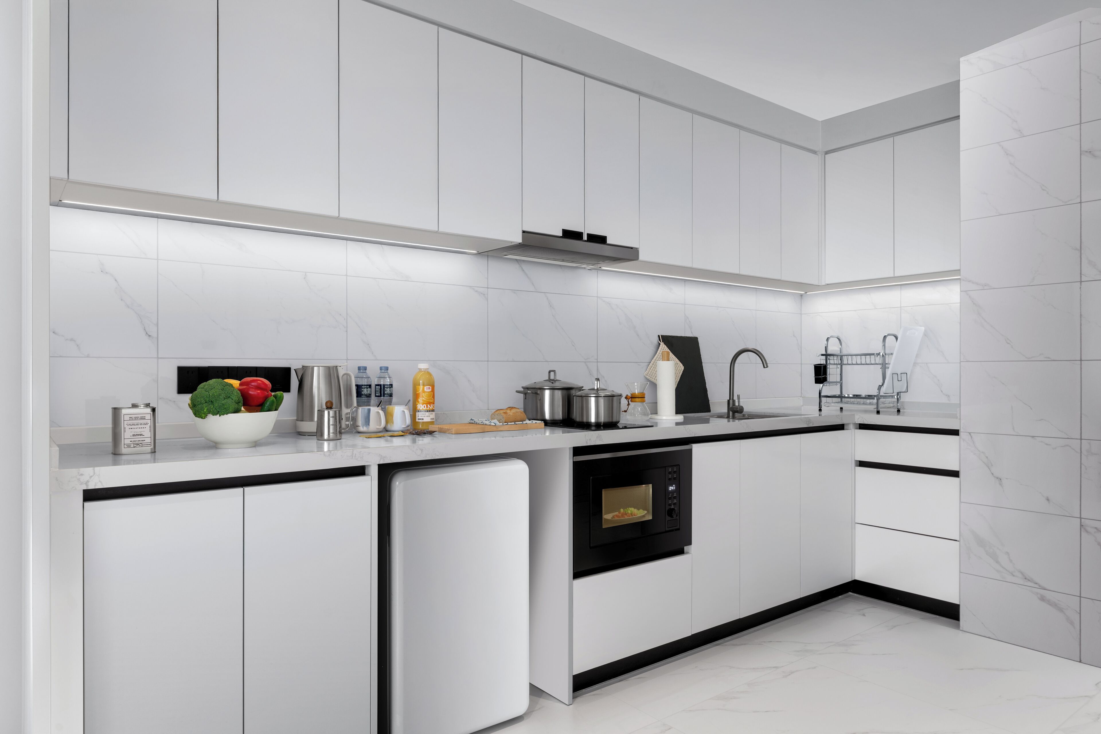 A modern kitchen with white cabinetry, a built-in oven, and a stainless steel sink.