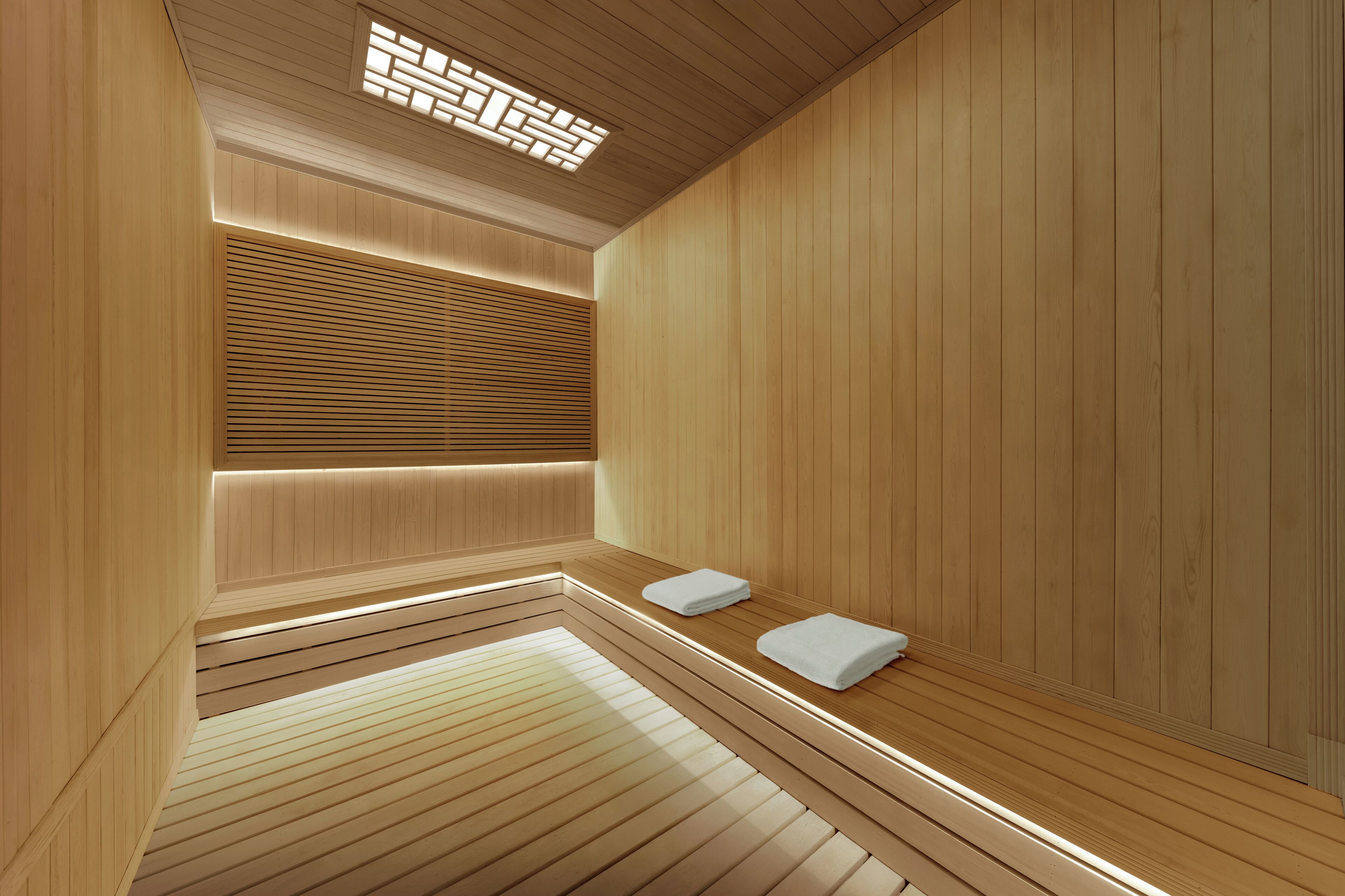 A wooden sauna with benches and a bench with towels.