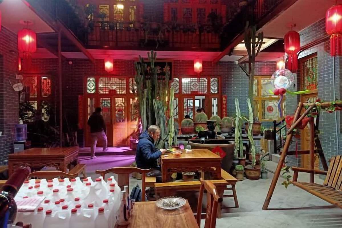 Un intérieur traditionnel avec des meubles en bois, un coin repas avec des tables, et une personne qui marche.