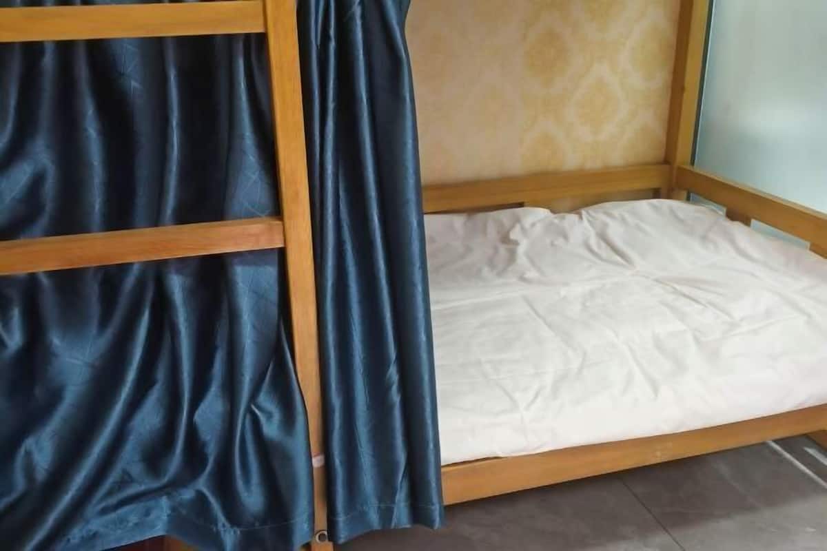 Un lit superposé avec un matelas blanc et un rideau bleu.