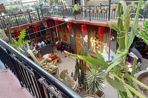 A courtyard with potted plants, a seating area, and a traditional building with red lanterns. - Pingyao Jiaxin Guesthouse (Pingyao County)