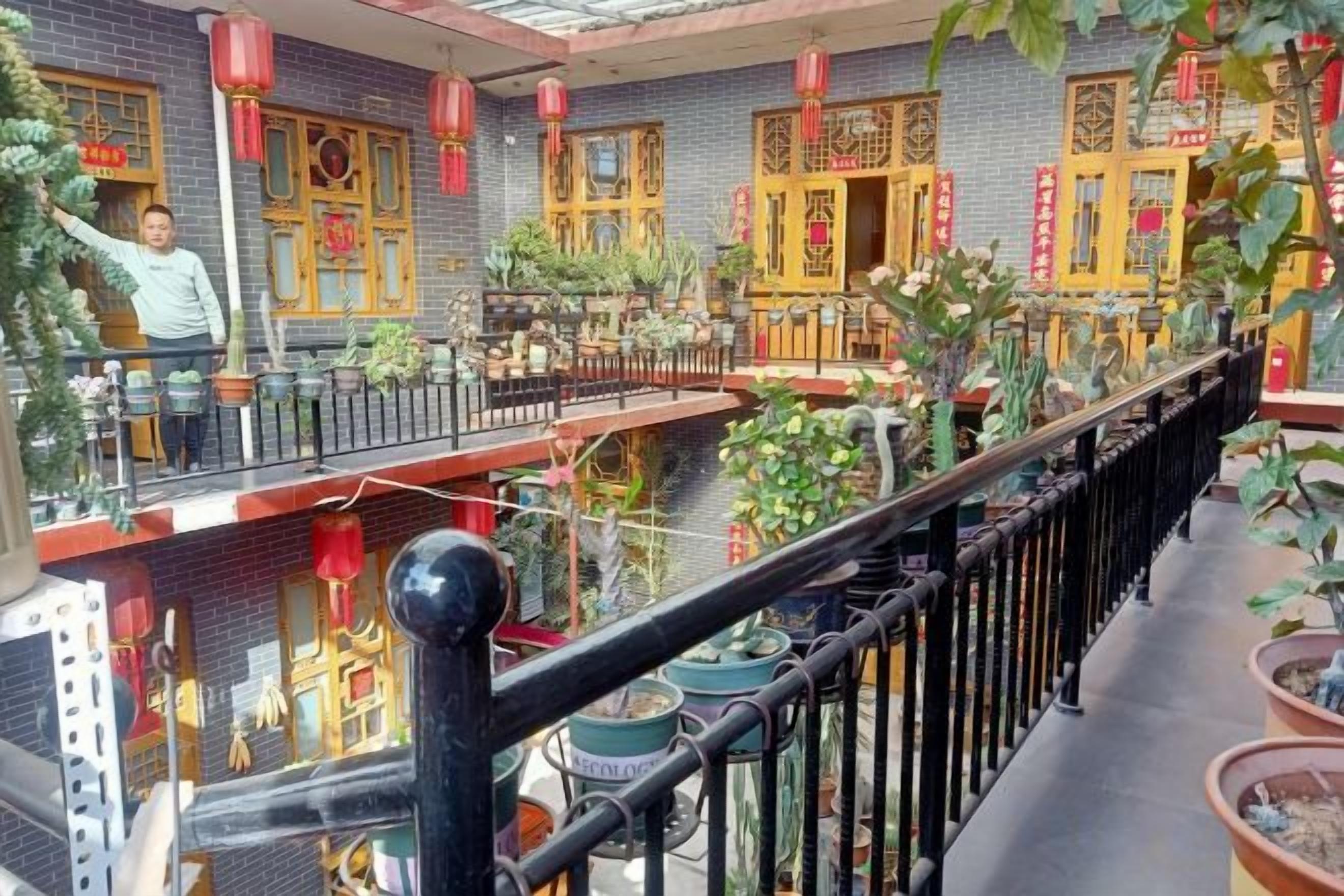 A traditional Chinese courtyard with tiled flooring, potted plants, and red lanterns.