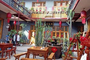 A traditional courtyard with wooden furniture, potted plants, and a balcony with red lanterns. - Pingyao Jiaxin Guesthouse (Pingyao County)