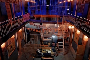 A multi-level interior with a central staircase, wooden railings, and a seating area with tables and chairs. - Pingyao Jiaxin Guesthouse (Pingyao County)