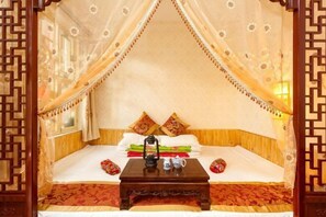 Ein traditionelles Bett mit Baldachin, ein Nachttisch mit Laterne und Kissen.