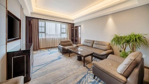 A modern living room with a sofa set, a coffee table, and a flat-screen TV. - Long Yang International Hotel (Hanshou)