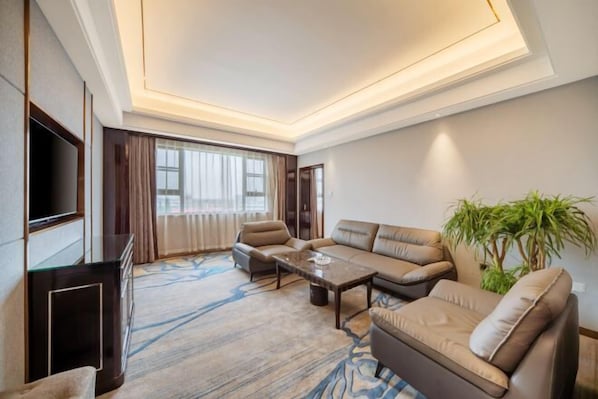 A modern living room with a sofa set, a coffee table, and a flat-screen TV. - Long Yang International Hotel (Hanshou)
