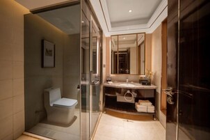 Un baño moderno con cabina de ducha de vidrio, inodoro blanco, tocador con espejo y perchero.
