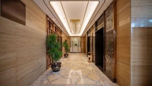 A hallway with a patterned floor, wooden paneling, and a chandelier. - Long Yang International Hotel (Hanshou)