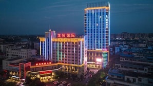 A hotel with a prominent vertical light strip and a tall building with a blue facade. - Long Yang International Hotel (Hanshou)