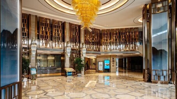 A spacious lobby with a geometric marble floor, a central chandelier, and a reception desk. - Long Yang International Hotel (Hanshou)