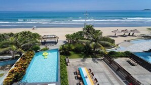 A pool area with a view of the beach and ocean.
