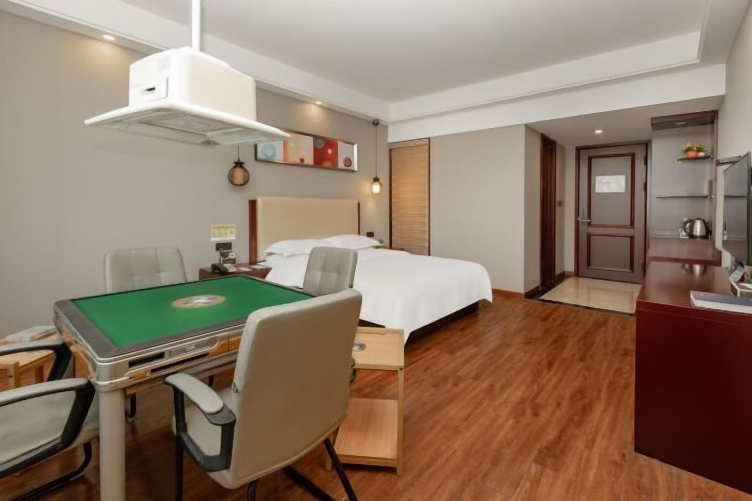 Une chambre d’hôtel avec une table de billard verte, un lit, un bureau et une kitchenette.