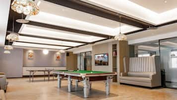 A modern indoor space with a pool table, seating area, and a billiards setup.