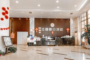 A hotel reception area with a modern design, a reception desk, and a wall-mounted sign. - Jie Te holiday inn (Wenling)
