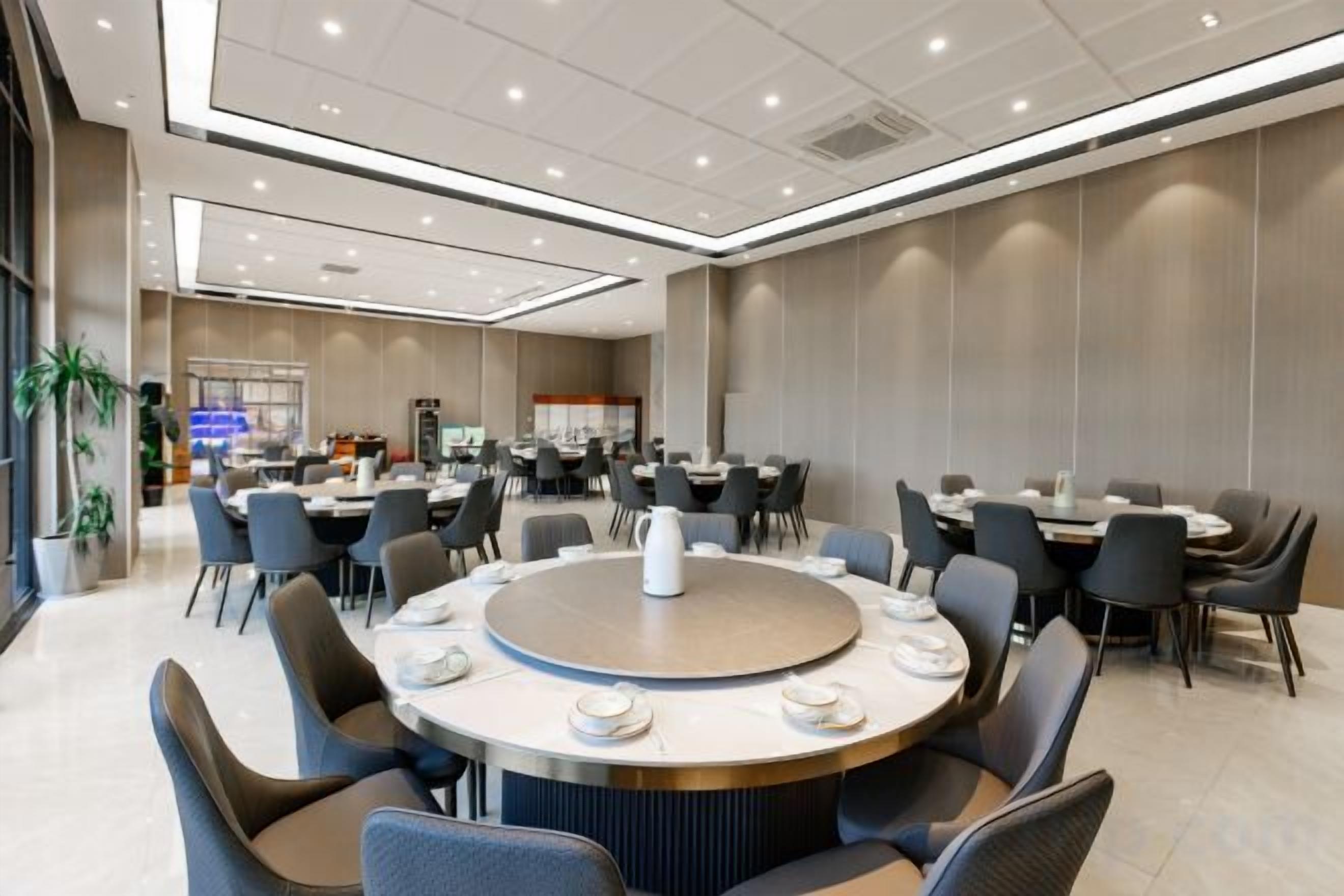 En modern hotellrestaurang med runda bord, stolar och en buffé.
