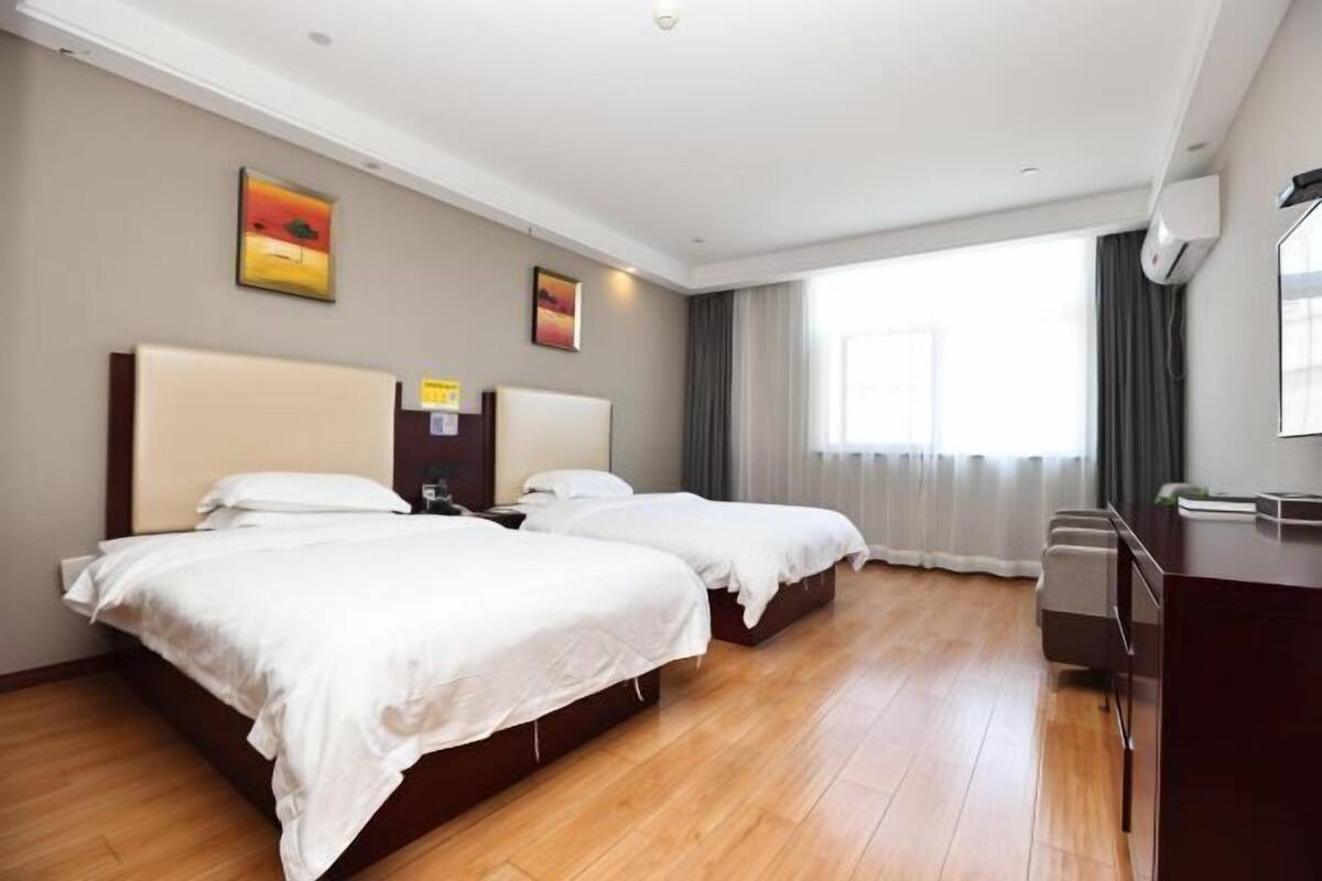 Habitación de hotel con dos camas, un escritorio y un ventanal grande.