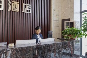 A reception desk with a wooden panel background, a potted plant, and a water dispenser.