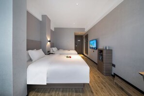 A modern hotel room with a large bed, a television, and a minibar. - Xiamen Kangheng Yijing Hotel (Gaoqi Airport Houpu Subway Station) (Xiamen)