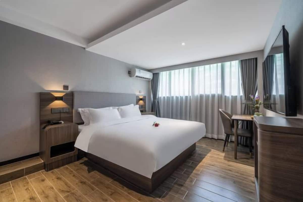 A modern hotel room with a large bed, a desk, and a TV.
