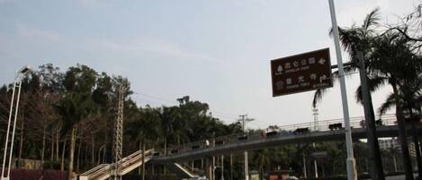 A street scene with a pedestrian overpass, a signboard, and a car.