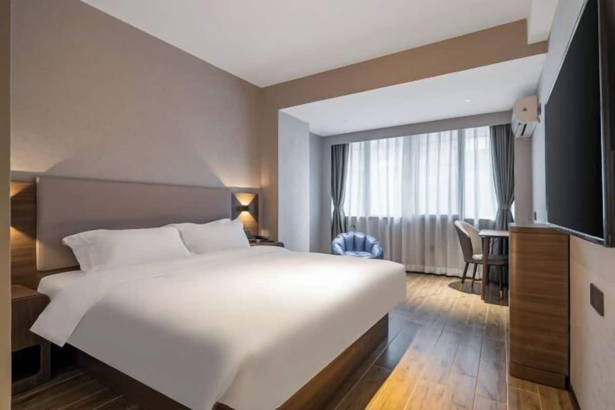 A modern hotel room with a large bed, a desk, and a chair.