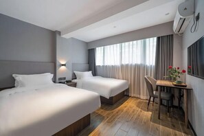 A hotel room with two beds, a desk, and a chair. - Xiamen Kangheng Yijing Hotel (Gaoqi Airport Houpu Subway Station) (Xiamen)