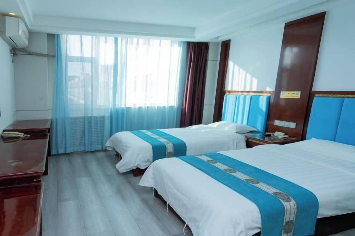 Hotelkamer met twee bedden, een bureau, een stoel en een raam met gordijnen.