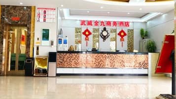 Ein Hotel-Empfangsbereich mit einer Rezeption, einer Uhr und einem roten Schild mit chinesischen Schriftzeichen.